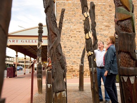 Man and Woman looking at the Story Poles located at the exterior of the Gallery